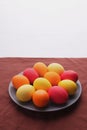 on table is plate with colored eggs on white background. Yellow, orange and red eggs. Selective focus Royalty Free Stock Photo