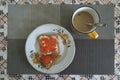 On the table is a plate with sandwiches with butter and red caviar. Nearby is a cup of coffee with milk