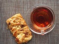 On the table is a puff pastry bun with sweet filling and pecan kernels and a Cup of tea Royalty Free Stock Photo