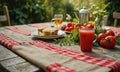 A table with a red and white checkered tablecloth is set with food and drinks. There are two plates of food, one of whic