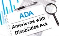 On the table are reports, diagrams, a pen, a magnifying glass and a white notepad with ADA Americans with Disabilities Act. Royalty Free Stock Photo