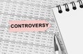 On the table among the reports is a notebook, a pen with an arrow with the inscription - Controversy Royalty Free Stock Photo