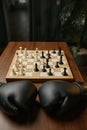 Table in room with boxer gloves and chessboard with chesspieces, chess conflict Royalty Free Stock Photo