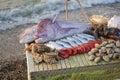 On the table are seafood: big fish, smaller fish, lobsters, mussels, oysters. The table stands on a pebble beach on the surf line