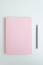 On the table is a secret diary of a girl. The cover of the notebook is a delicate pink color. Next to it is a pen for writing. The