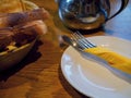 Table served for breakfast, Bread, white plates with cutlery and napkin on a wooden table in a pub Royalty Free Stock Photo