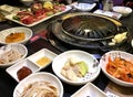 Table served for cooking Korean barbecue, kimchi, vegetables, pickled onions, garlic, meat on porcelain plates and with a disc for