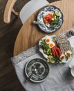 A table set for breakfast, brunch - a plate with crispy bread, lightly salted salmon, avocado, boiled eggs on a round wooden table