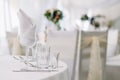 Table set for an event party or wedding reception on white tablecloth. White soft background with tables and flowers Royalty Free Stock Photo