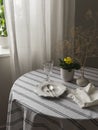A table set for lunch - a plate, cutlery, glasses on a round table with a linen tablecloth, flowers in a pot in the living room Royalty Free Stock Photo