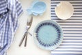 Table set in marine style - empty plates in shape of fish, blue glass, fork and knife on striped napkins on white background. Royalty Free Stock Photo