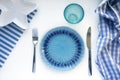 Table set in marine style - empty plates in shape of starfish, blue glass, fork and knife on striped napkins on white background. Royalty Free Stock Photo