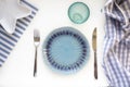 Table set in marine style - empty plates in shape of starfish, blue glass, fork and knife on striped napkins on white background. Royalty Free Stock Photo