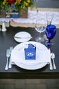 Table setting for a wedding celebration in an outdoor mission style patio with blue and orange theme, and flower decorations Royalty Free Stock Photo