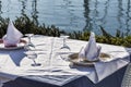Table set by the sea with white tablecloth, wine glasses, well-folded napkins and porcelain dishes Royalty Free Stock Photo