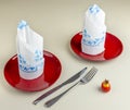 A table is set with two red plates with two white napkins decorated in blue on top Royalty Free Stock Photo