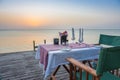 Table set for two on sea coast. Romantic table setting on the sunset. Outdoor restaurant on the beach. Elegant cafe decoration. Royalty Free Stock Photo