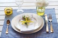 Table setting with blue checkered tablecloth, white napkin and y Royalty Free Stock Photo