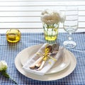 Table setting with blue checkered tablecloth, white napkin and y Royalty Free Stock Photo