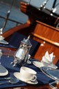 A table setting with silver teapot for breakfast on the luxury wooden big yacht.