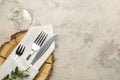 table setting. cutlery. glass, fork, knife in a white napkin and a wooden stand on a light concrete table. top view Royalty Free Stock Photo