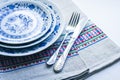 Table setting for dinner: white and blue plates, a fork, a knife on a woven cloth napkin with an embroidered pattern,  traditional Royalty Free Stock Photo