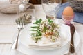 Table setting for Easter, white plates, napkin, bouquet of flowers, green leaves, quail eggs, outdoors, kinfolk