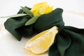 Table setting element lemon slice on a plate, green cloth napkin and yellow flower Royalty Free Stock Photo