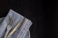 table setting with empty plate napkin fork and knife on black background Royalty Free Stock Photo