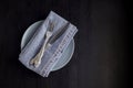 table setting with empty plate napkin fork and knife on black background Royalty Free Stock Photo