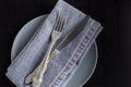 table setting with empty plate napkin fork and knife on black background Royalty Free Stock Photo