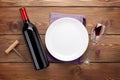 Table setting with empty plate, wine glass and red wine bottle Royalty Free Stock Photo