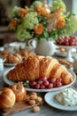 A table setting featuring a continental breakfast with croissants, a variety of fresh fruits, and flowers in vase Royalty Free Stock Photo