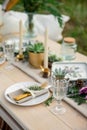 Decorated elegant wooden table in rustic style with eucalyptus and flowers, porcelain plates, glasses, napkins and cutlery Royalty Free Stock Photo