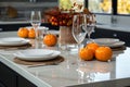 Table setting with pumpkins, plates and glasses in modern kitchen at home