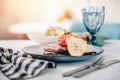 Table setting in restaurant is fresh meat steak with pear and tomato decoration. Cutlery and wine glass Royalty Free Stock Photo