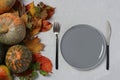 Table setting on Thanksgiving Day decorated pumpkin and colorful leaves on grey background. Space for text.