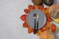 Table setting on Thanksgiving Day decorated pumpkin, pears and colorful leaves on grey background. Space for text.