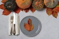 Table setting on Thanksgiving Day decorated pumpkin, pears and colorful leaves on grey. View from above