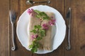 Table setting with twig ornamental currant twig on burlap napkin and white plate, forged fork, knife and little spoon on vintage