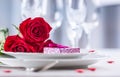 Table setting for valentines or wedding day with red roses. Romantic table setting for two with roses plates cups and cutlery