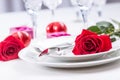 Table setting for valentines or wedding day with red roses. Romantic table setting for two with roses plates cups and cutlery Royalty Free Stock Photo