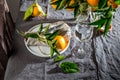 Table setting with white plate, cutlery, linen napkin and orange tree branch decoration on gray linen tablecloth . Close