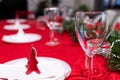 Table setup lunch in red for celebration. Shiny glass cup, red tablecloth, candles and decorations with green Christmas tree. Royalty Free Stock Photo