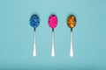 Table spoons filled with assortment of various colourful pills on blue pastel coloured background. Medication.