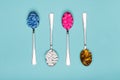 Table spoons filled with assortment of various colourful pills isolated on blue pastel coloured background. Antiobesity medication Royalty Free Stock Photo