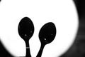 Table spoons in silhouette against a circular light like plate