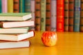 On the table are stacks of books and an apple. Royalty Free Stock Photo