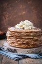 On the table on a stand made of wood cut a pile of thin pancakes