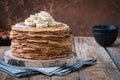 On the table on a stand made of wood cut a pile of thin pancakes